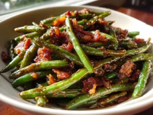 Close-up of bright green beans tossed in a savory glaze with crispy bacon pieces, highlighting the delicious green beans.