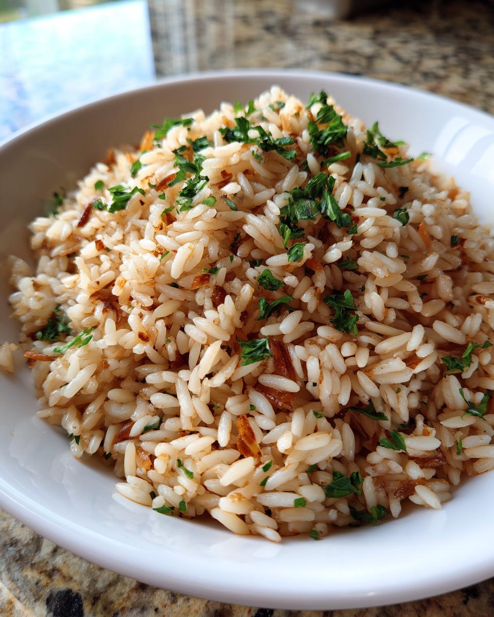 A close-up of fluffy, perfectly cooked rice pilaf topped with fresh chopped parsley in a white bowl.