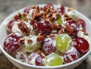 Close-up of creamy chicken salad chick grape salad mixed with red and green grapes and topped with pecans.
