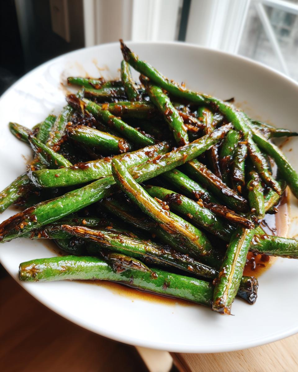 A white bowl filled with vibrant, blistered chinese green beans with garlic sauce.