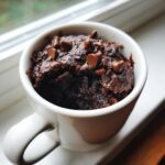 A rich, dark chocolate Cottage Cheese Microwave Brownie topped with chocolate chips, served in a white mug.