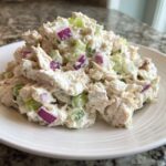 Close-up of a generous serving of creamy cottage cheese chicken salad mixed with diced red onion and celery.