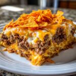 A generous slice of Dorito Casserole featuring layers of seasoned ground beef, melted cheese, and topped with crunchy Doritos.