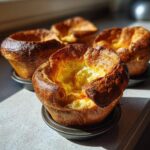 Close-up of a golden brown, fluffy Yorkshire pudding with a deep well, fresh from the oven.