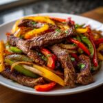 Close-up of perfectly cooked steak fajitas strips mixed with vibrant red, yellow, and green bell peppers and onions.