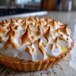 Close-up of a golden-brown, perfectly peaked meringue topping on a classic lemon meringue pie.