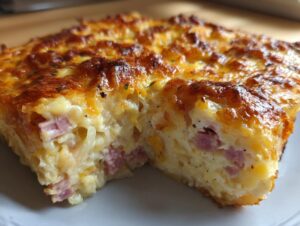 Close-up of a rich, cheesy slice of scalloped potatoes and ham with a golden-brown, bubbly top.