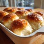 Close-up of a pan of soft dinner rolls with a shiny, buttery glaze, ready to serve.