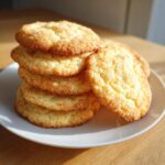 A stack of five golden, soft sugar cookie treats coated in cinnamon sugar, resting on a white plate.