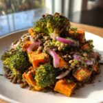 Close-up of a vibrant veggie lentil salad featuring lentils, roasted sweet potato cubes, broccoli florets, and red onion slices.