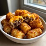 Close-up of crispy tater tot casserole bites stuffed with ground beef and melted cheddar cheese.
