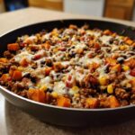 Close-up of a savory sweet potato skillet with ground meat, black beans, corn, and melted cheese.