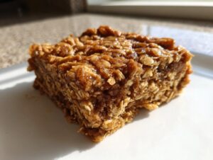 A single, thick, chewy square of brown sugar oatmeal bars sitting on a white plate.