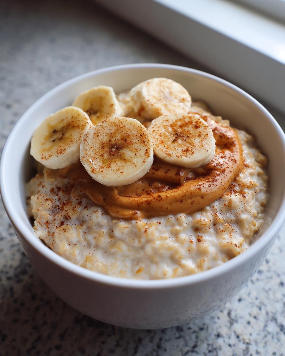 Close-up of creamy banana oatmeal topped with a swirl of peanut butter, sliced bananas, and cinnamon.