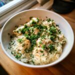 A close-up of creamy one pot chicken and rice topped generously with fresh chopped parsley in a white bowl.