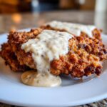 Close-up of crispy, golden-brown chicken fried steak smothered in creamy, speckled country gravy.