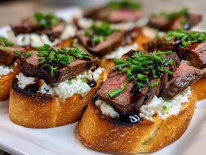 Close-up of perfectly cooked steak crostini topped with creamy cheese, medium-rare steak slices, and fresh chives.