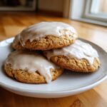 A stack of three soft maple brown sugar cookies topped with a thick, light brown glaze, resting on a white plate.