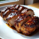 Close-up of a juicy, sliced pork tenderloin recipe covered in a thick, dark, glistening glaze.