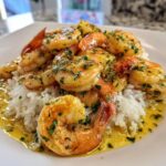 Close-up of succulent Hawaiian garlic shrimp served over a bed of fluffy white rice, coated in buttery garlic sauce and parsley.