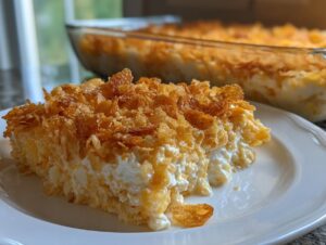 A generous slice of creamy hot chicken salad topped with a thick layer of crispy, golden cornflakes on a white plate.