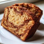 Close-up of two moist slices of cinnamon swirl apple bread on a white plate.