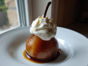 A beautifully glazed poached pear topped with whipped cream, served in a white bowl with syrup.