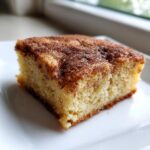 A close-up, tasty shot of a single square of soft snickerdoodle blondies topped with cinnamon sugar.
