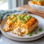 A square serving of baked buffalo chicken dip, topped with melted cheddar and fresh green onions.