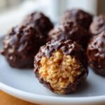 Close-up of a chocolate rice krispie balls with a bite taken out, showing the crispy interior.