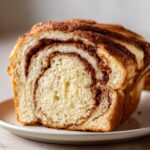 Close-up of a freshly baked slice of cinnamon swirl bread showing soft interior and rich cinnamon layers.
