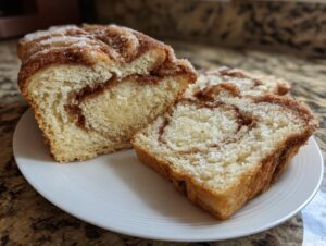 Close-up of two thick slices of soft cinnamon swirl bread showing the rich interior swirl.