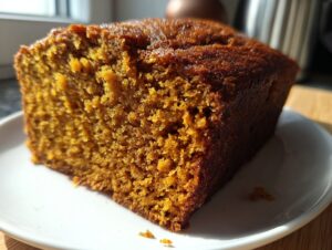 Close-up of a thick, moist slice of easy pumpkin bread showing its rich orange crumb texture.