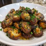 A close-up of savory Garlic butter mushrooms, glistening with sauce and topped with fresh parsley.