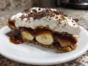 Close-up of a decadent slice of no-bake banoffee pie showing banana, caramel, and whipped cream topping.