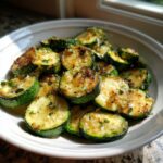 Close-up of golden brown, perfectly sauteed zucchini rounds seasoned with herbs and garlic.
