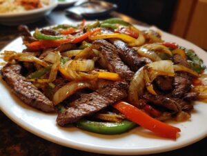 Close-up of perfectly cooked steak fajita strips mixed with sautéed onions and colorful bell peppers.