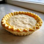 Close-up of an unbaked, perfectly crimped pie crust dough ready for filling.