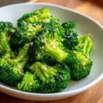Close-up of bright green steamed broccoli florets seasoned with garlic and spices in a white bowl.