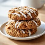 Three delicious coffee cake cookies stacked on a white plate, topped with a zigzag white glaze.