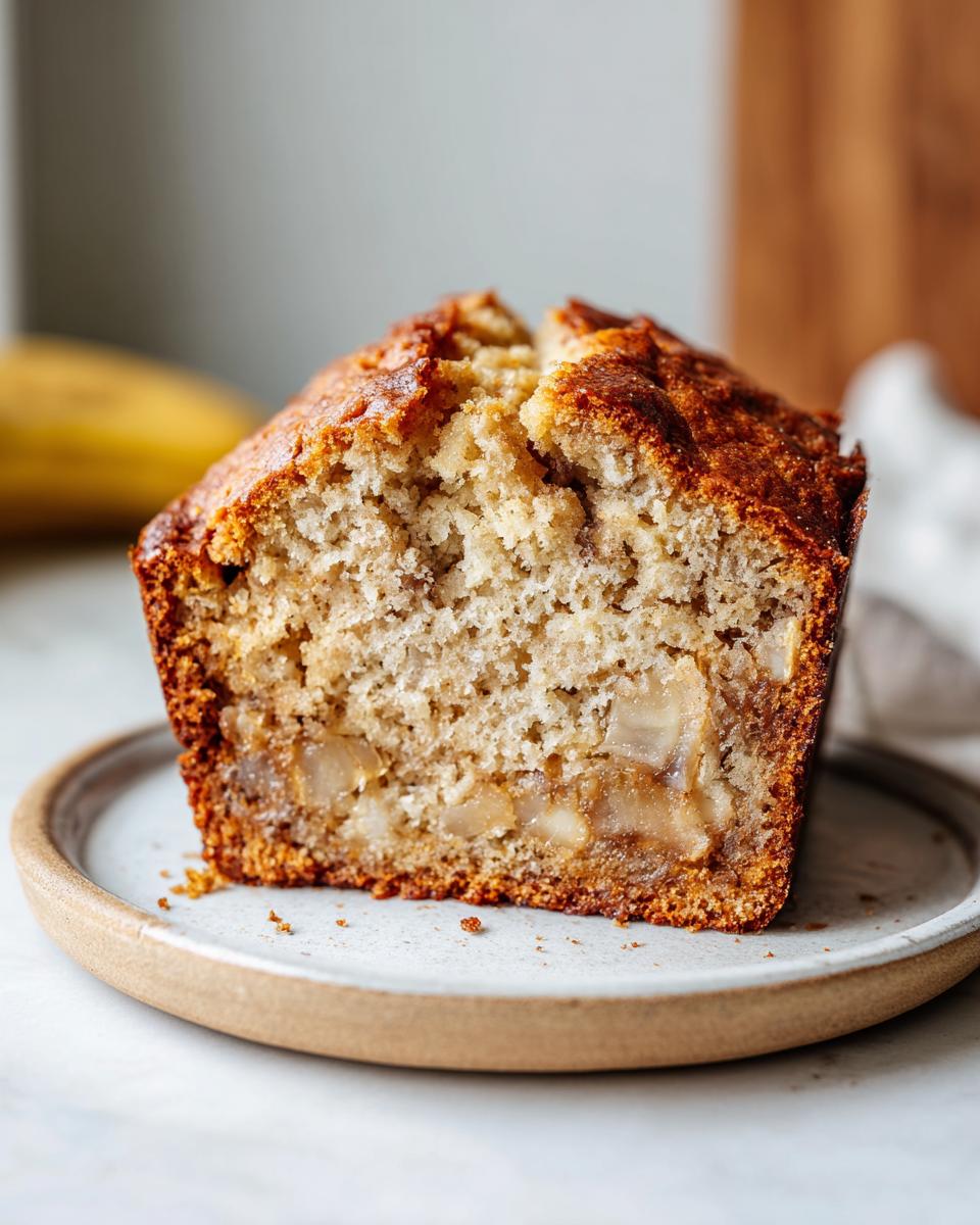 Close-up of a moist slice of greek yogurt banana bread showing its soft crumb and caramelized banana pieces.