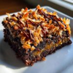 A decadent square of Samoa box mix brownies featuring a gooey caramel layer, toasted coconut, and a chocolate drizzle.