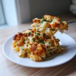 A serving of cheesy shrimp scampi pasta bake with a fork lifting a cheesy portion, showing long cheese pulls.