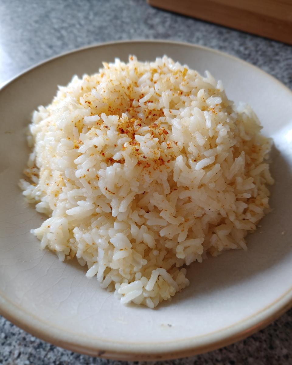 A mound of fluffy white rice seasoned with spices, resembling texas roadhouse seasoned rice, served in a light-colored bowl.